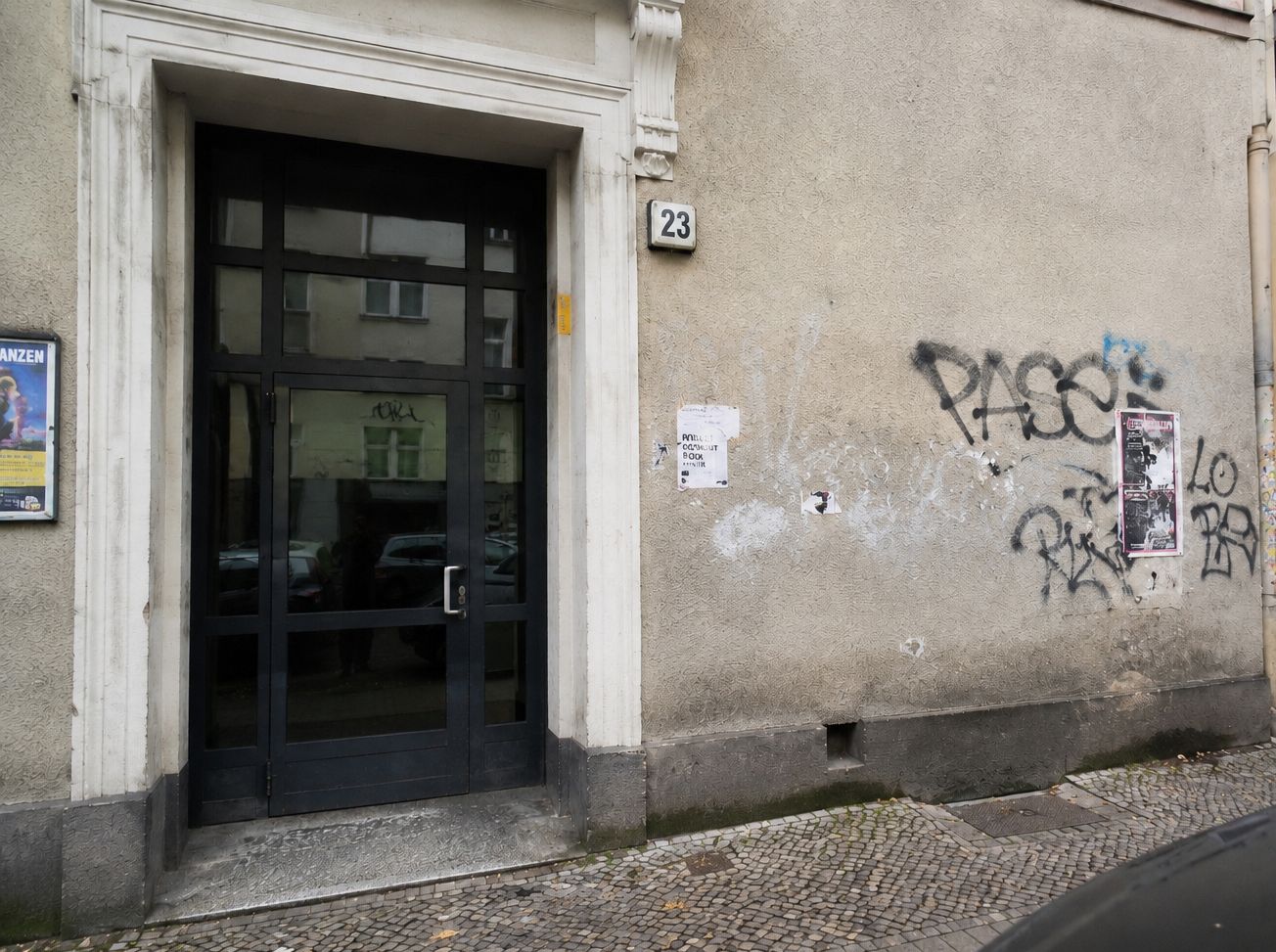 Hauswand mit Eingangstür, Hausnummer 23 und Graffiti — Beispiel für eine typische öffentliche Außenfläche